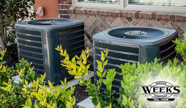 Two HVAC units outside in bushes