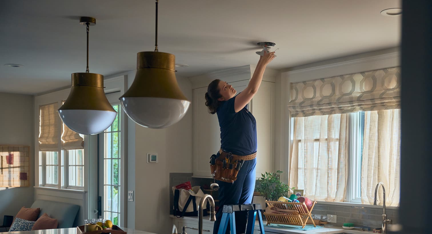 A professional Weeks Service Company electrician standing on a ladder to install modern recessed ceiling lights during a residential electrical installation service.